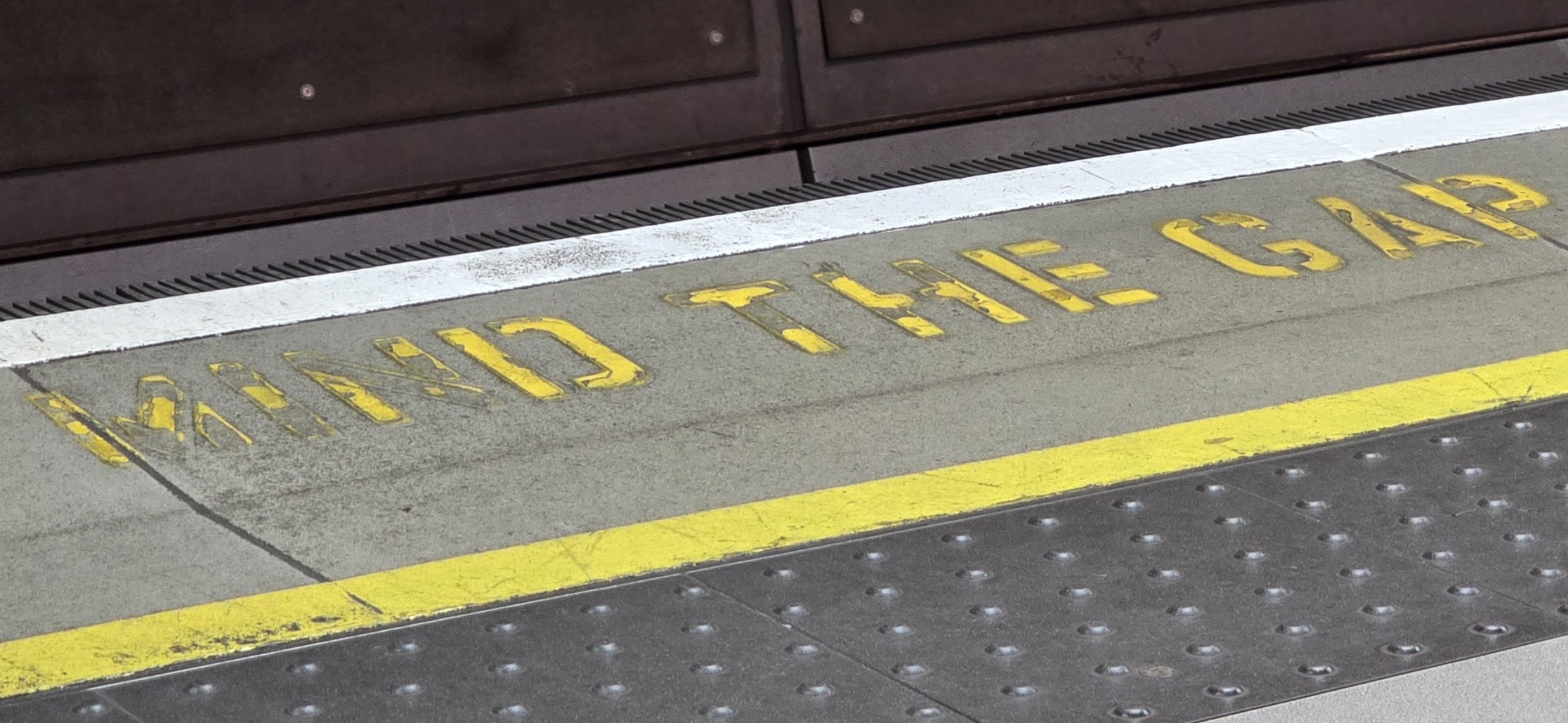 Photograph of London subway walk with the iconic "mind the gap" painted in yellow
